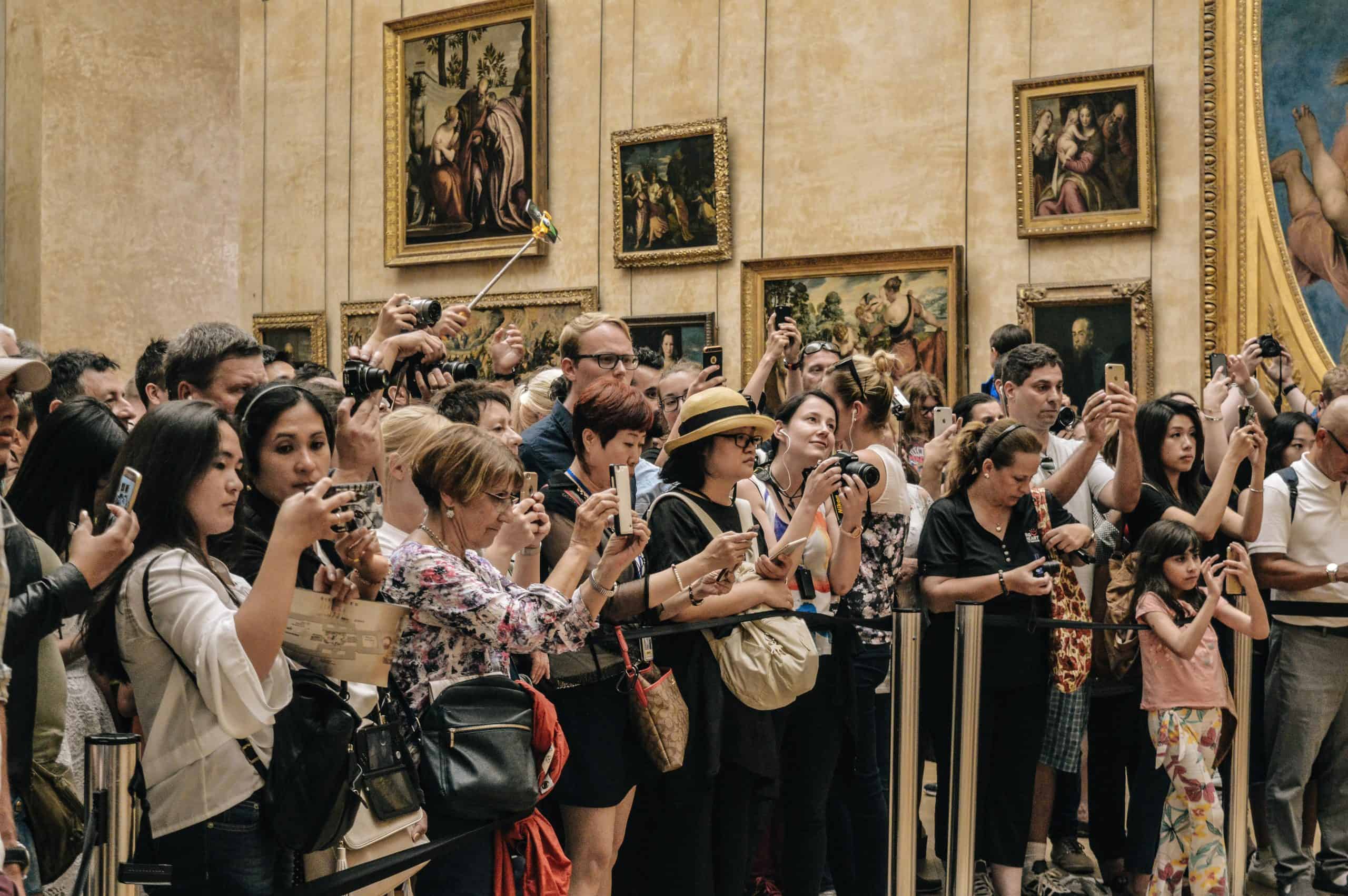 Crowd of people clustered together in a museum taking photographs