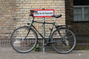 Bicycle parked on street in front of sign that says "fläche für die feuerwehr" which translates to "area for the fire brigade"