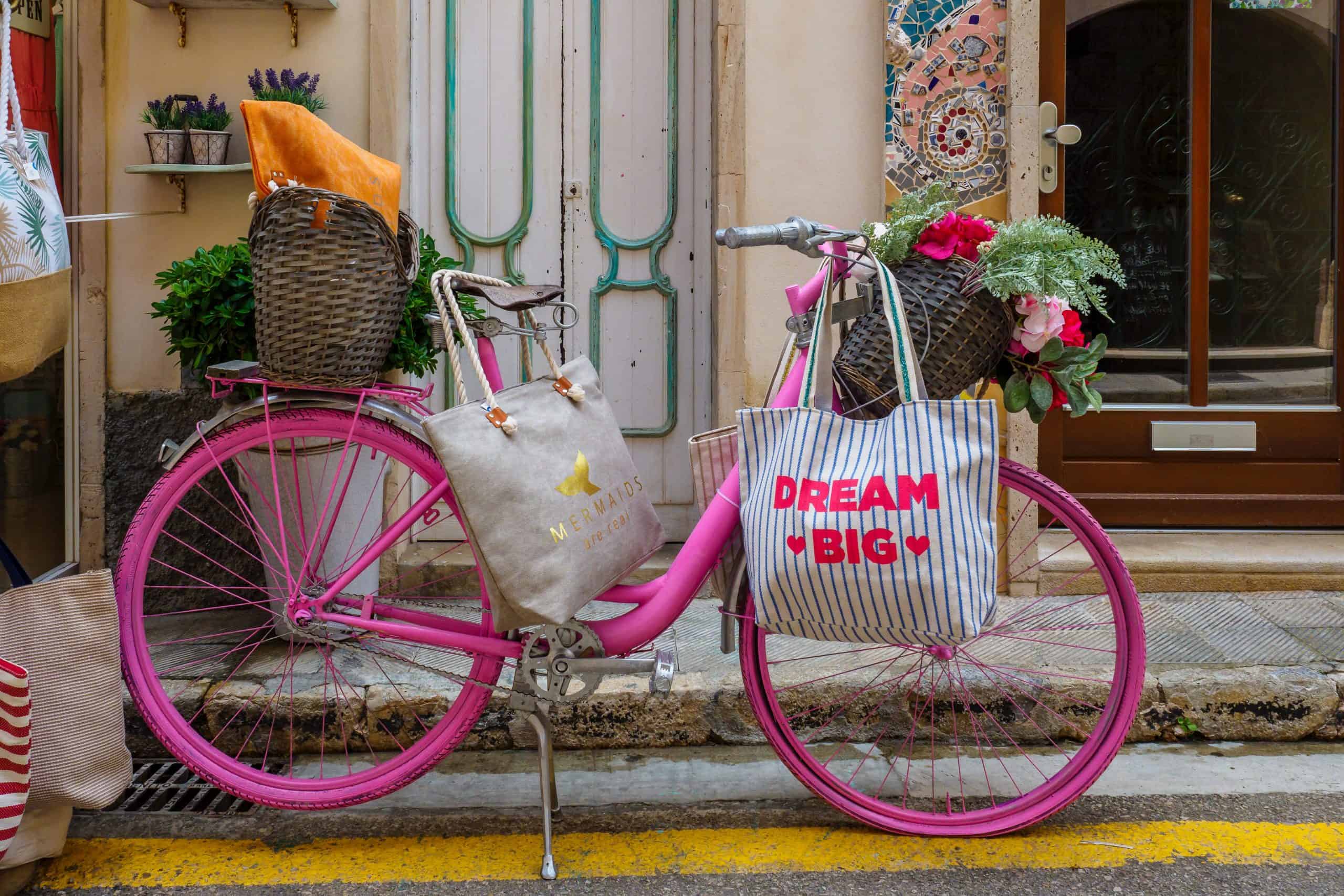 Pink bicycle parked in front of colorful house