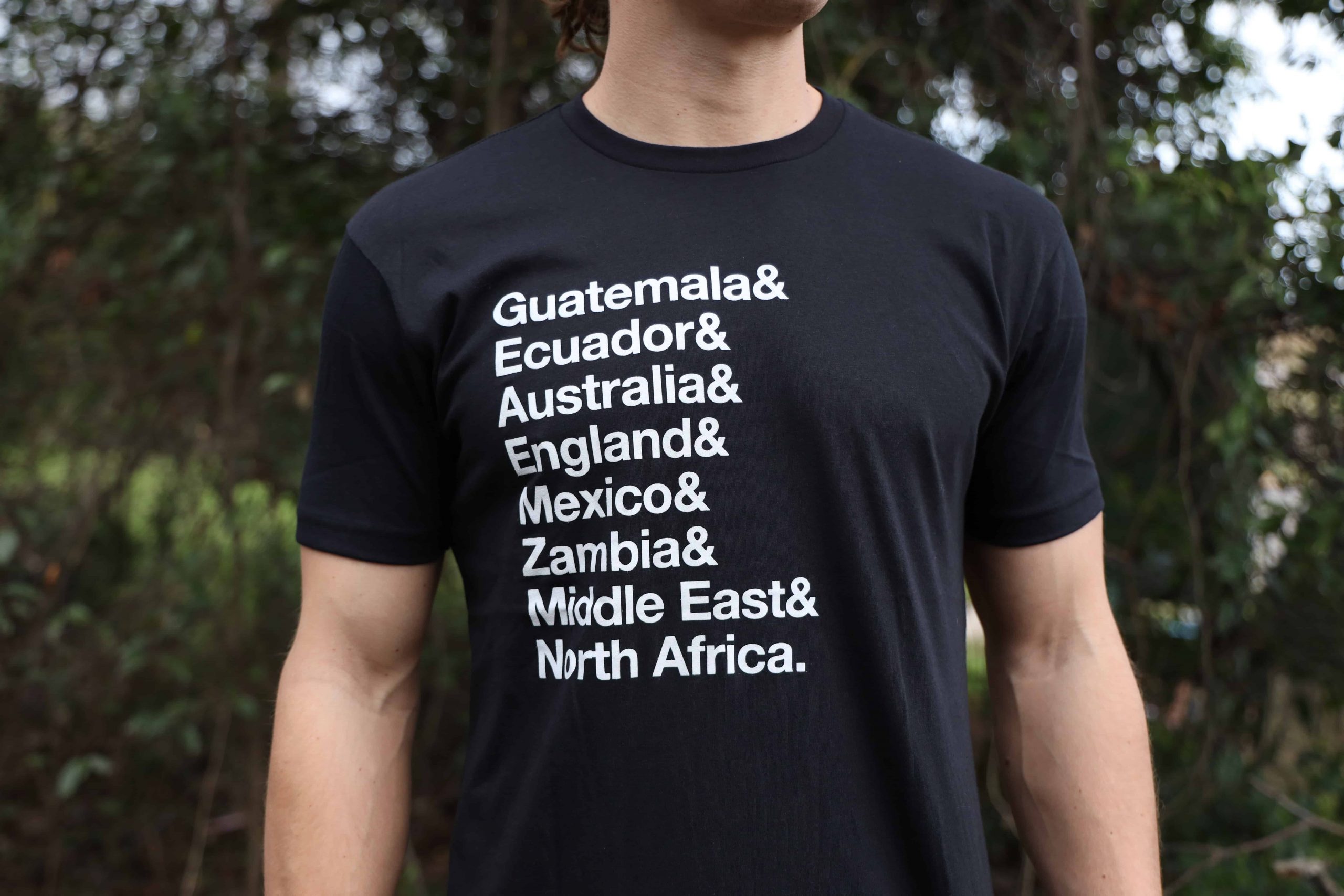 Man wearing black shirt that says "Guatemala & Ecuador & Australia & England & Mexico & Zambia & Middle East & North Africa"