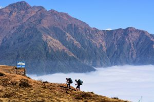 Two men hiking up cloudy mountainside