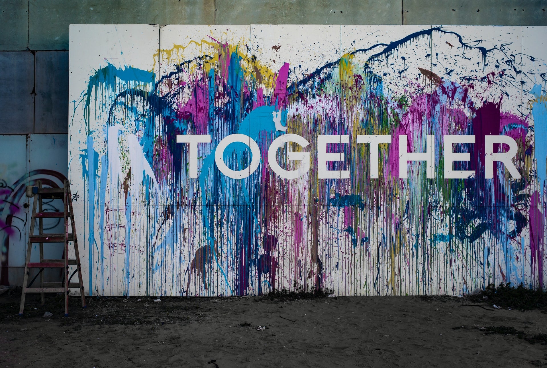 A wall covered in paint splatters with the word "Together" painted on it