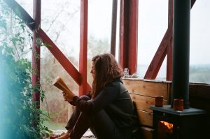 Woman sitting by a wood furnace reading