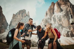 Group of travelers laughing together at the base of mountains