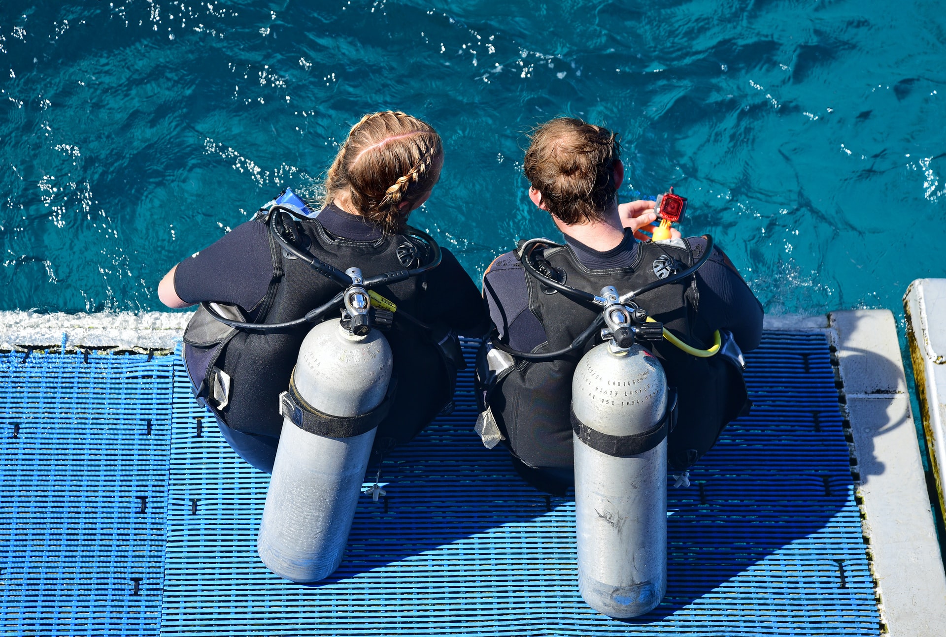 Two scuba divers sitting on the edge of the water