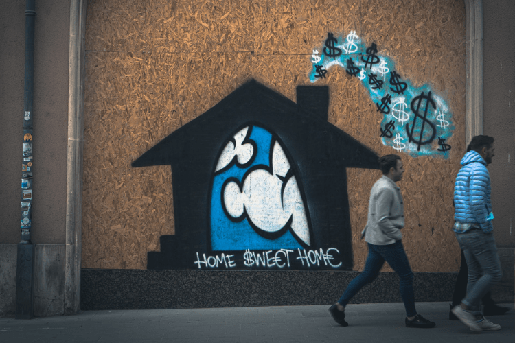 Two men walking past graffiti that reads, "Home sweet home"