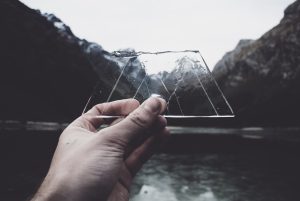 A piece of glass being held against a mountainous backdrop