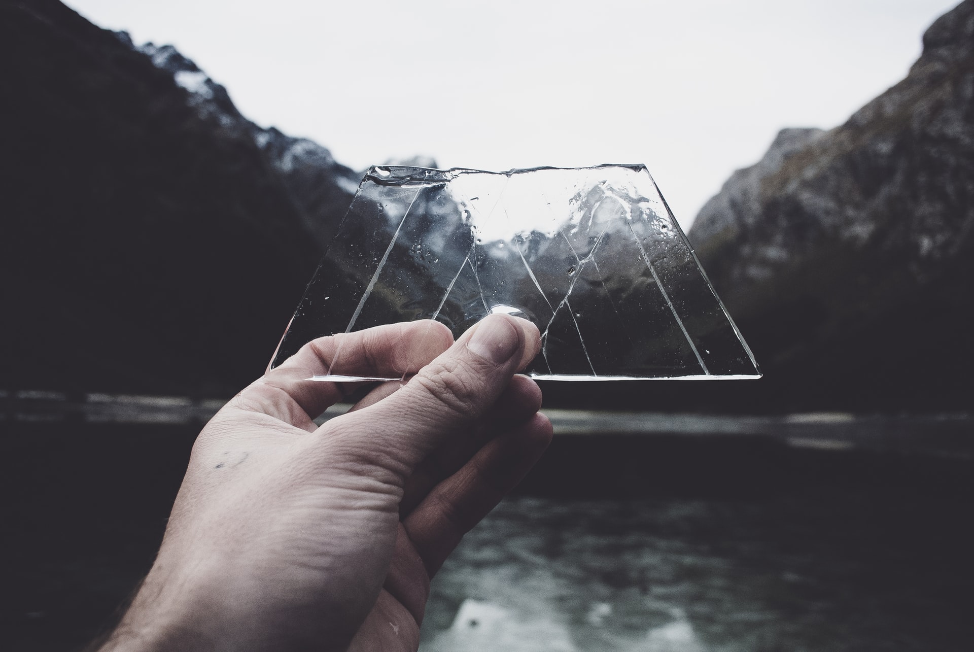 A piece of glass being held against a mountainous backdrop