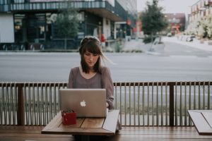 Woman working on laptop at an outdoor restaurant